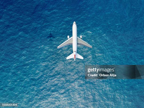 vliegtuig vliegt over een zee - landing stockfoto's en -beelden