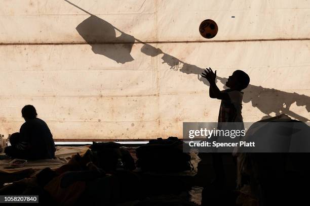 Child plays with a ball as members of the Central American migrant caravan rest in a stadium after arriving into the Mexican capital yesterday on...