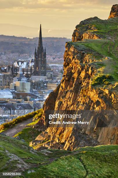 rocky cliffs of salisbury crags in holyrood park with edinburgh city the in background at sunset - holyrood park 個照片及圖片檔