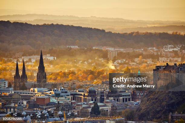 edinburgh cityscape and mountains on skyline with st mary's cathedral steeples and autumn trees - edinburgh scotland stockfoto's en -beelden