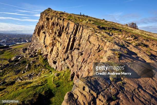 rocky landscape of salisbury crags, holyrood park with edinburgh city the in background at sunset - western europe stock pictures, royalty-free photos & images