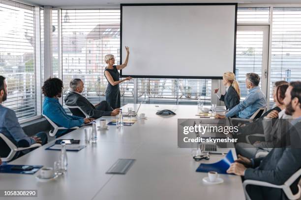 mature ceo giving a business presentation through projection screen in a board room. - projection equipment stock pictures, royalty-free photos & images