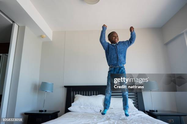 joven saltando en la cama - a boy jumping on a bed fotografías e imágenes de stock