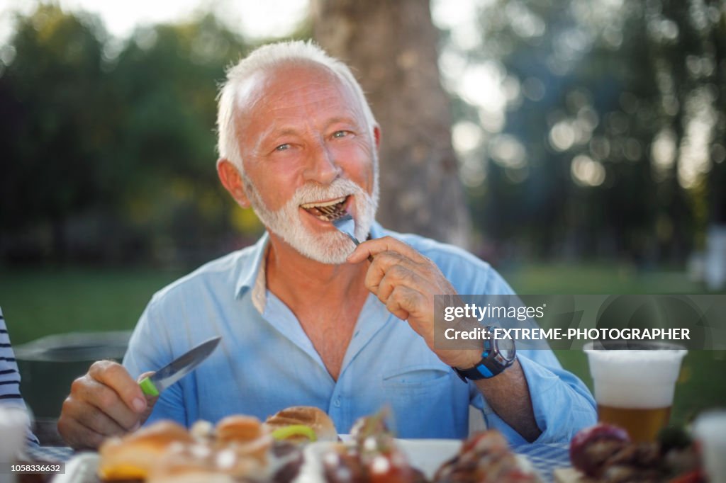 Senior man eating food during a picnic