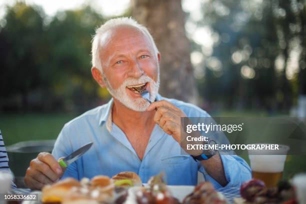 senior man eating food during a picnic - senior men beer stock pictures, royalty-free photos & images