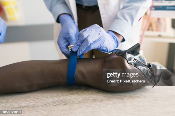 close up medical student tying tourniquet on fake arm - tourniquet stock pictures, royalty-free photos & images