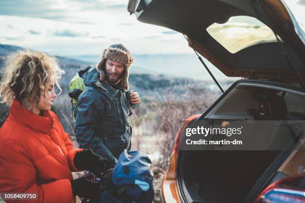 couple on hiking taking backpacks from the car trunk - winter wilderness stock pictures, royalty-free photos & images