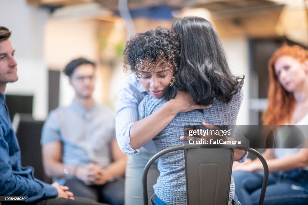 Two women hugging during a support group meeting