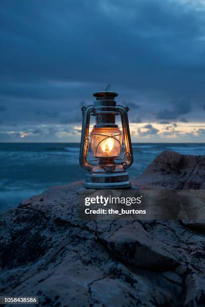 still life of lantern standing on rocks by the sea - lantern water stock-fotos und bilder