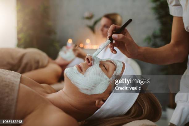 mother and adult daughter enjoy beauty treatment in a spa center - group of people wearing masks stock pictures, royalty-free photos & images