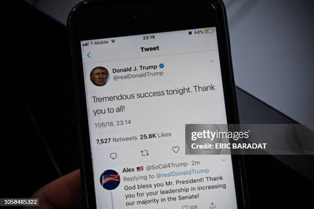 Smartphone shows a tweet by US President Donald Trump saying "Tremendous success tonight" after most of the result of the US midterm elections were...