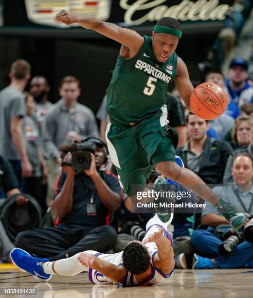 Cassius Winston of the Michigan State Spartans leaps over Devon Dotson of the Kansas Jayhawks during the game at Bankers Life Fieldhouse on November...