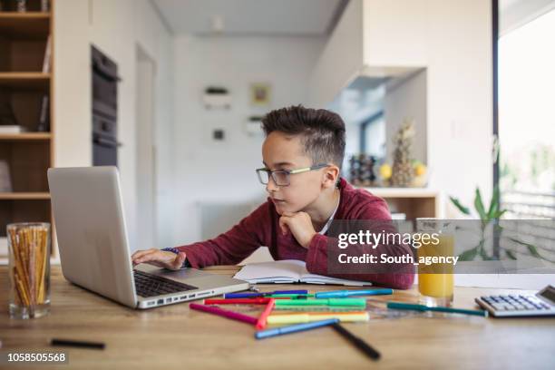 chico haciendo la tarea en la computadora portátil - niño de primaria fotografías e imágenes de stock