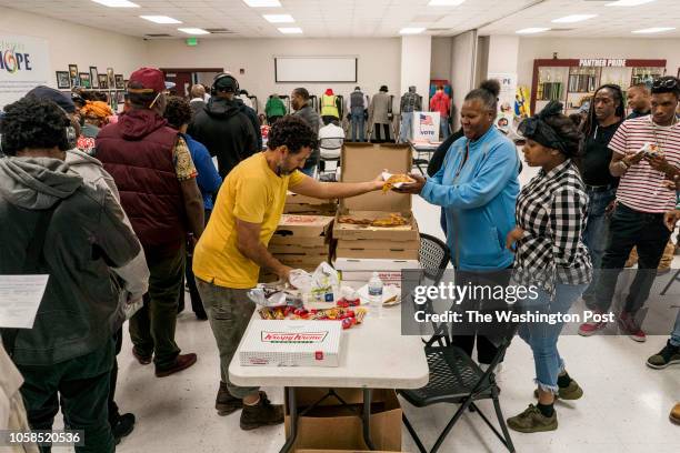 On election day at Pittman Park Recreation center polling location thousands of American voters stand line to vote, being fed pizza and other stacks...