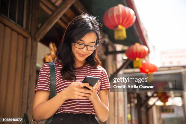 cheerful young woman checking phone in chinatown - perth street stock pictures, royalty-free photos & images