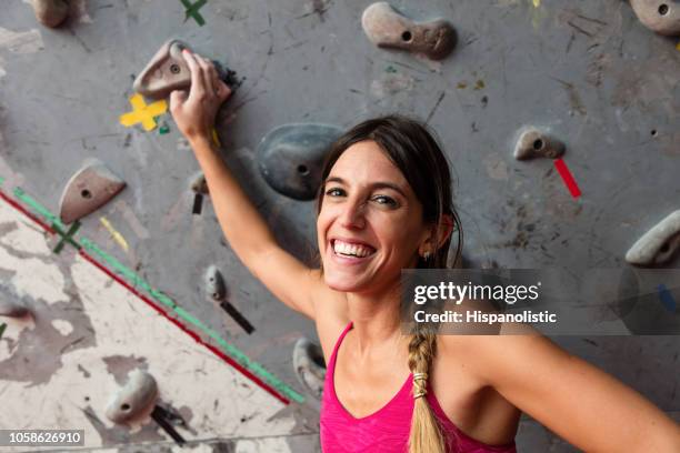 portrait of a youg woman at an indoor climbing wall looking at camera smiling - bouldern indoor stock pictures, royalty-free photos & images