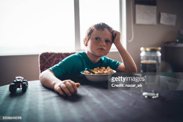 farmers kid on table with cornflakes in bowl. - new zealand farmer stock pictures, royalty-free photos & images