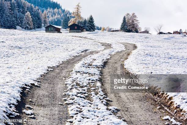 dirt road in the snow ground, european alps - tyre stockfoto's en -beelden