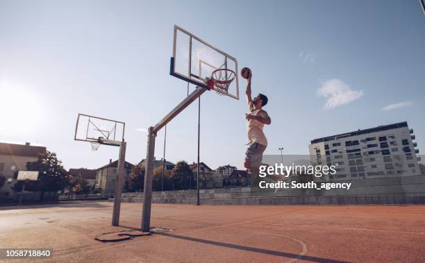 jeune homme sauter et faire un fantastique slam dunk - match basket photos et images de collection