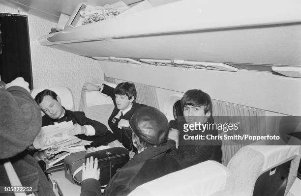 Members of The Beatles on board a plane bound for Paris, January 1964. Left to right: manager Brian Epstein , Paul McCartney, John Lennon and George...