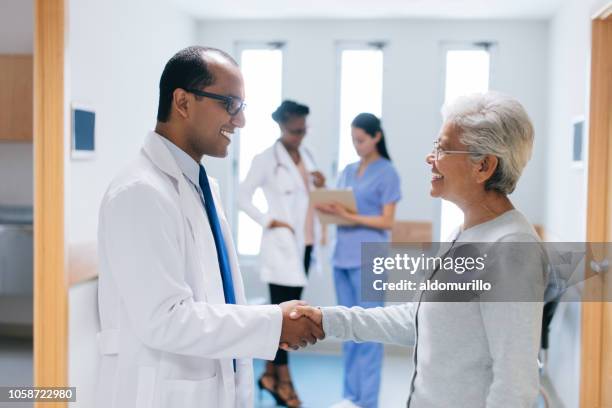 latin doctor and patient shaking hands in hospital hall - doctor general practitioner stock pictures, royalty-free photos & images