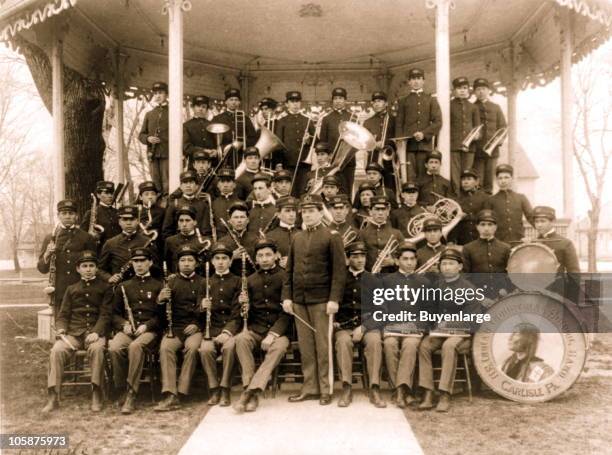The Carlisle Indian School music band posed in their uniforms at the bandstand, Carlisle, PA, 1901.