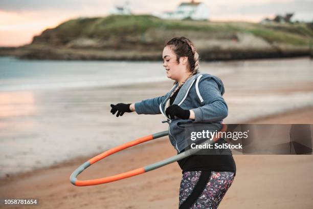 young woman using a weighted hula hoop - jogar ao arco imagens e fotografias de stock