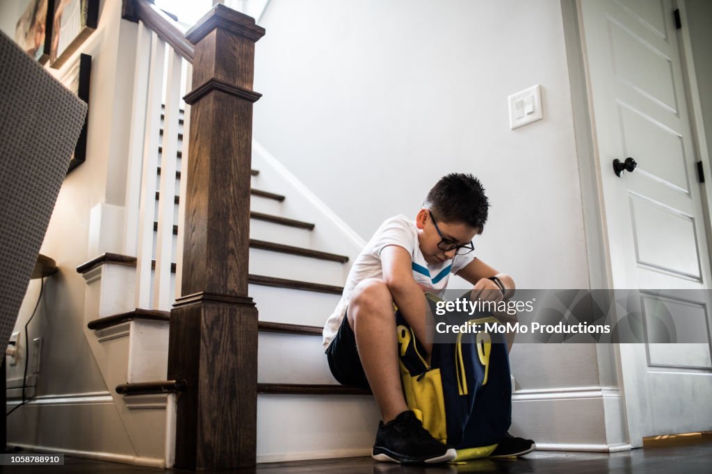 School age boy looking through backpack