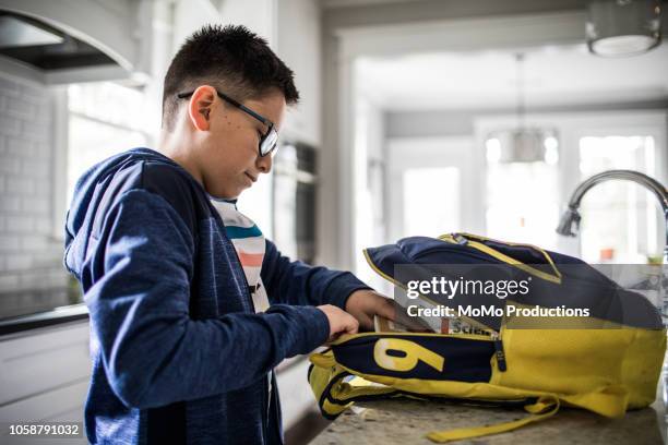 school age boy looking through backpack - boy wearing backpack stock pictures, royalty-free photos & images