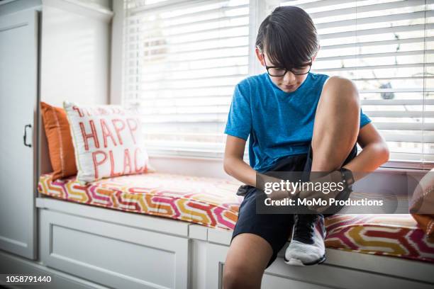 boy (11yrs) getting ready for school at home - boy tying shoes stock pictures, royalty-free photos & images