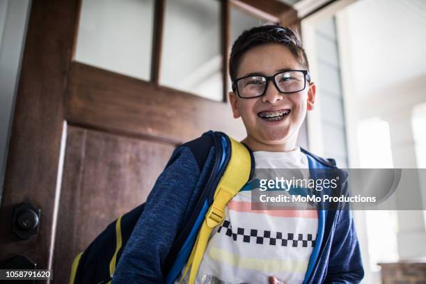 school age boy smiling and leaving for school - kind vor der pubertät stock-fotos und bilder