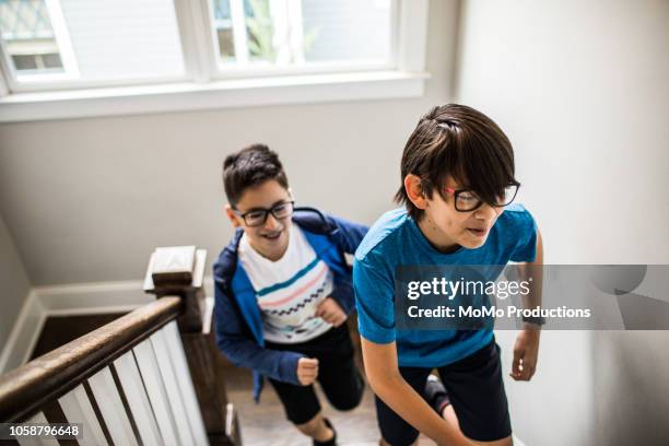 young boys running up stairs at home - boys wrestling stockfoto's en -beelden