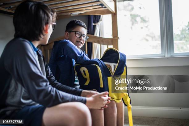 school age brothers talking on bed - kids open backpack stock pictures, royalty-free photos & images