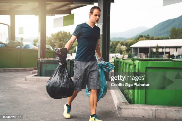 volwassen man op zoek naar plastic recycle container te dumpen in de prullenbak zakken ful van kunststof - garbage man stockfoto's en -beelden