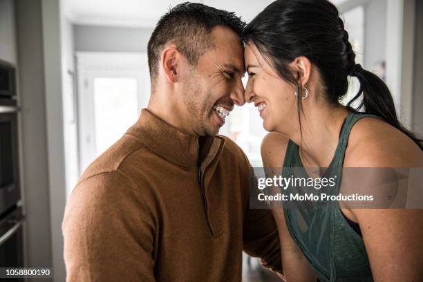 husband and wife hugging in kitchen - hispanic couple stock pictures, royalty-free photos & images