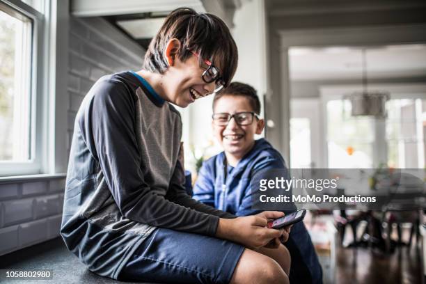 school age boys playing with smartphones - 10-15 2018 stock pictures, royalty-free photos & images
