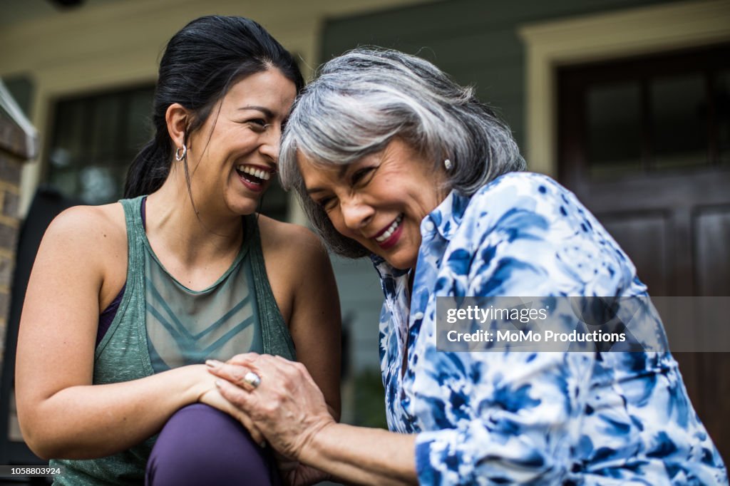 Senior woman and adult daughter laughing on porch
