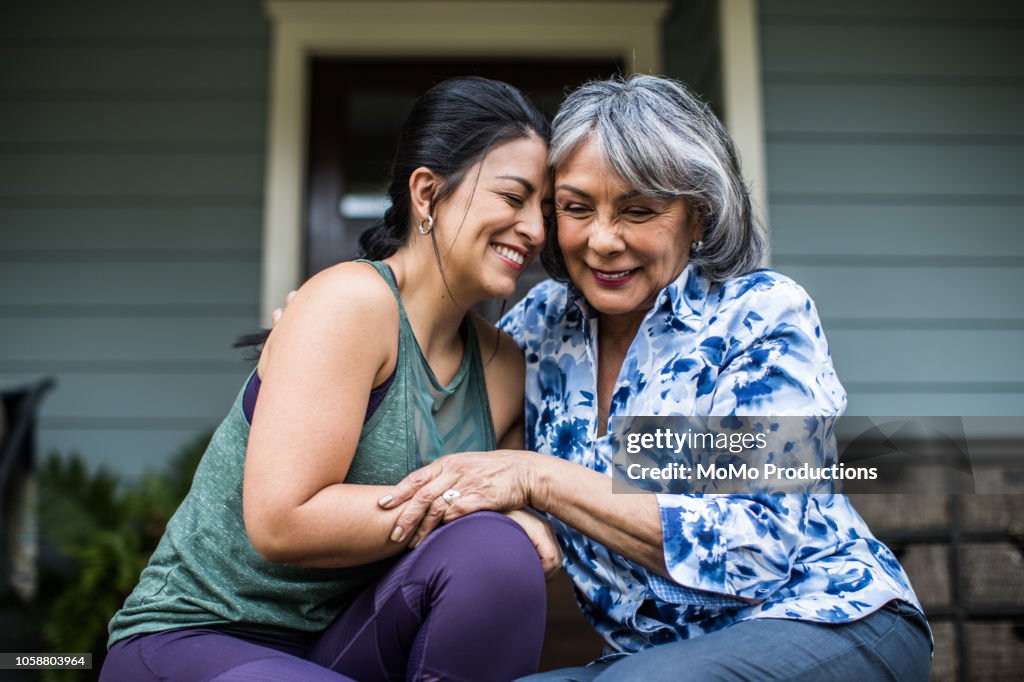Senior woman and adult daughter laughing on porch