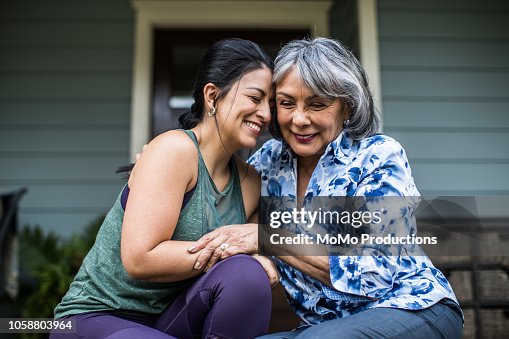 Senior woman and adult daughter laughing on porch Senior woman and adult daughter laughing on porch