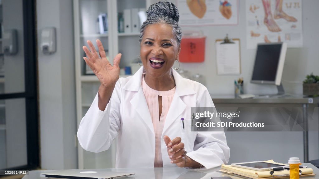 Ärztin-Wellen in die Kamera während der Web-Konferenz