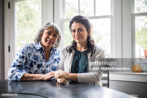 portrait of senior woman and adult daughter in kitchen - senior man grey long hair stock-fotos und bilder