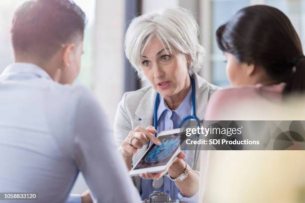 female neurologist discusses brain scan with husband of patient - neurologist stock pictures, royalty-free photos & images