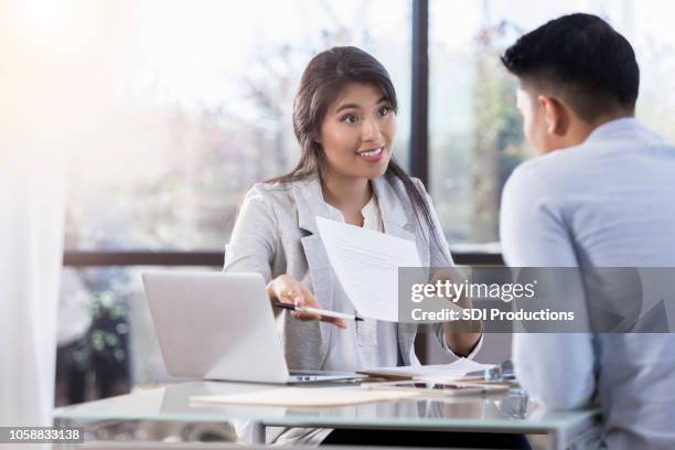 female financial adviser gestures to paper while instructing her client - future proof stock pictures, royalty-free photos & images