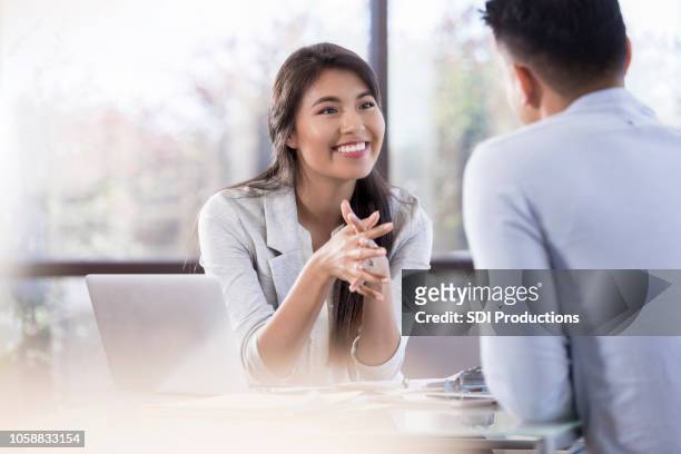 jonge vrouwelijke professionele glimlach op haar collega tijdens de vergadering - story telling in the workplace stockfoto's en -beelden
