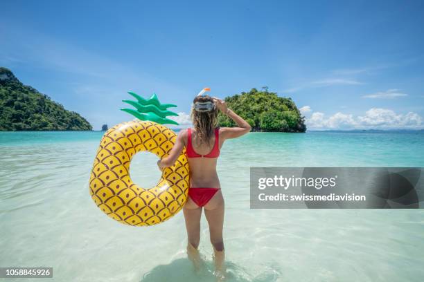 young woman standing on tropical beach with pineapple boat looking at islands - floating on water stock pictures, royalty-free photos & images