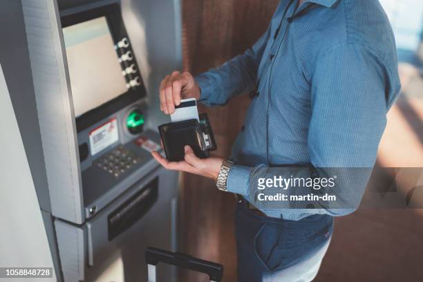 passagier mit kreditkarte am geldautomaten am flughafen - bank interior stock-fotos und bilder