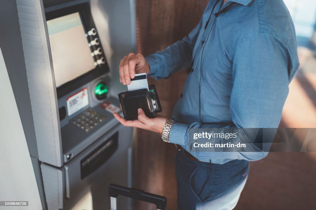 Pasajeros con tarjeta de crédito en el cajero automático en el aeropuerto