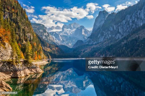 view of idyllic colorful autumn scenery with dachstein mountain at lake gosau - austria stock pictures, royalty-free photos & images