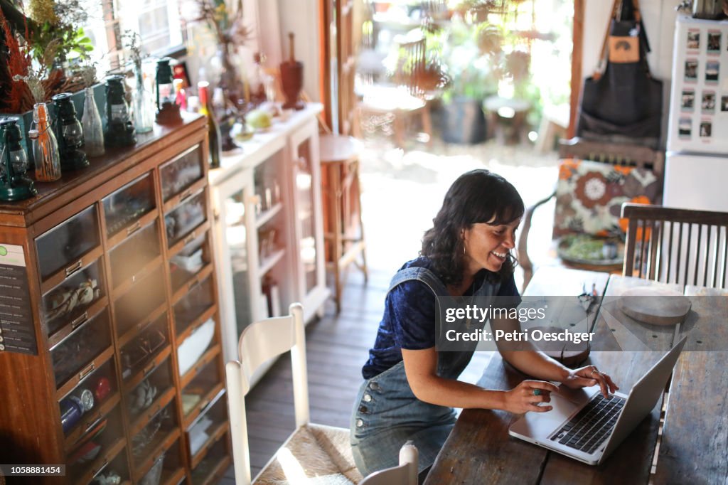 A Woman using her laptop in her kitchen at home.