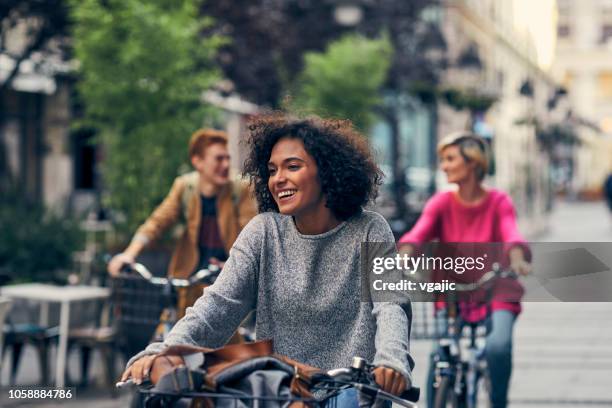 friends riding bicycles in a city - urban bicycle stock pictures, royalty-free photos & images